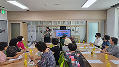 복지관 내부에서 한명의 전문가와 여러명의 노인들이 상담하고 있는 모습