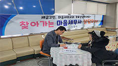 세금고민, 마을 세무사와 무료 상담하세요~찾아가는 마을세무사 상담day라고 적힌 현수막 앞에 앉아서 상담하고 있는 세무사와 노인의 모습