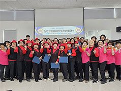 노인자원행사단(부라보)발대식 현수막이 띄워진 빔프로젝터 앞에서 단체로 포즈를 취하고 있는 노인자원행사단(브라보)단원들 모습