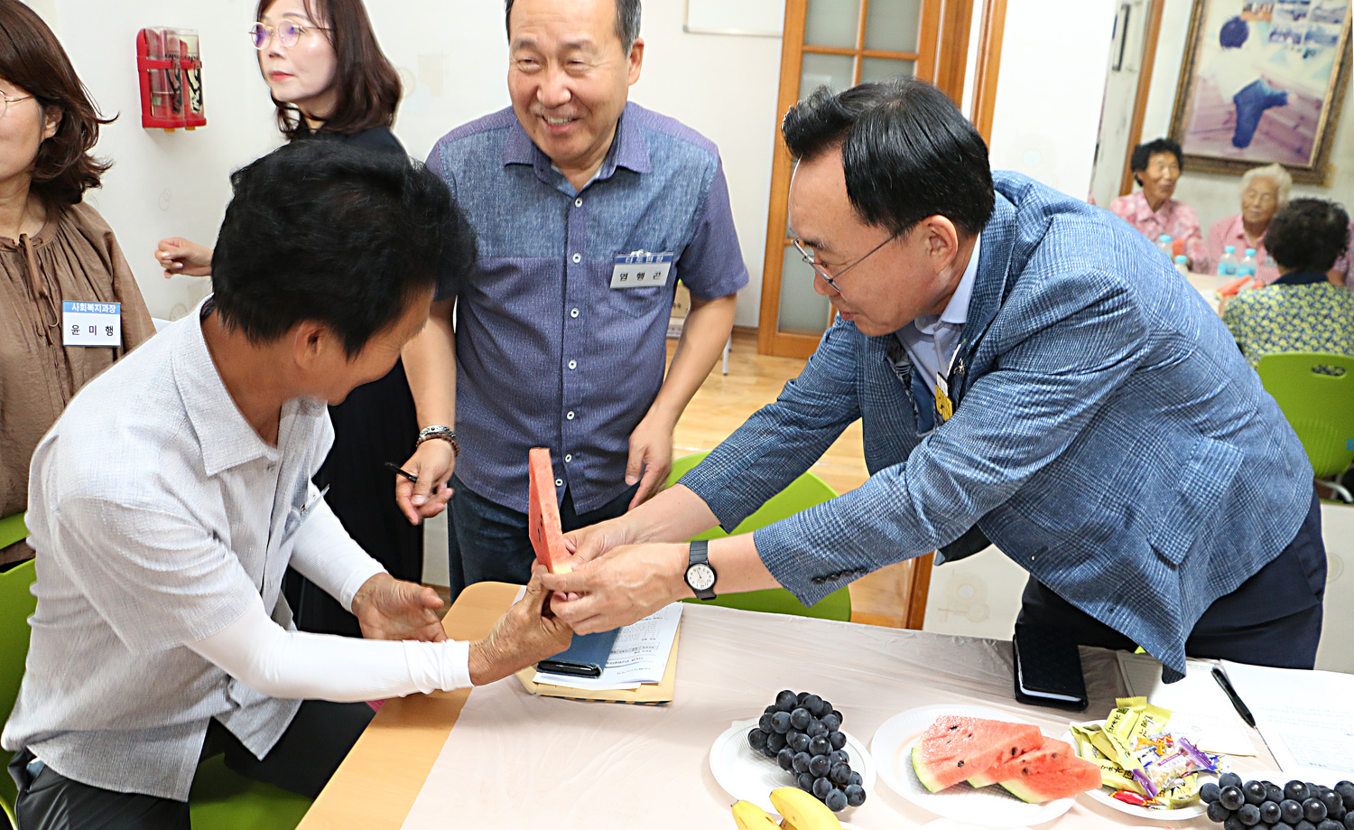 무더위 쉼터 현장 점검 나주시장이 자리에 앉아 있는 남성 어르신께 수박 한조각을 두손으로 드리고 있는 모습