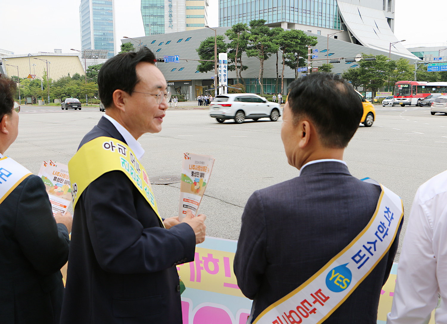 추석맞이 지역상품 판매 촉진 캠페인 및 청렴실천, 고향사랑 기부제 홍보 캠페인 인도에 서 있는 나주시장과 한전 KDN 사장의 뒷편에서 촬영한 모습 나주시장과 KDN사장이 이야기를 나누고 있ㄷ아