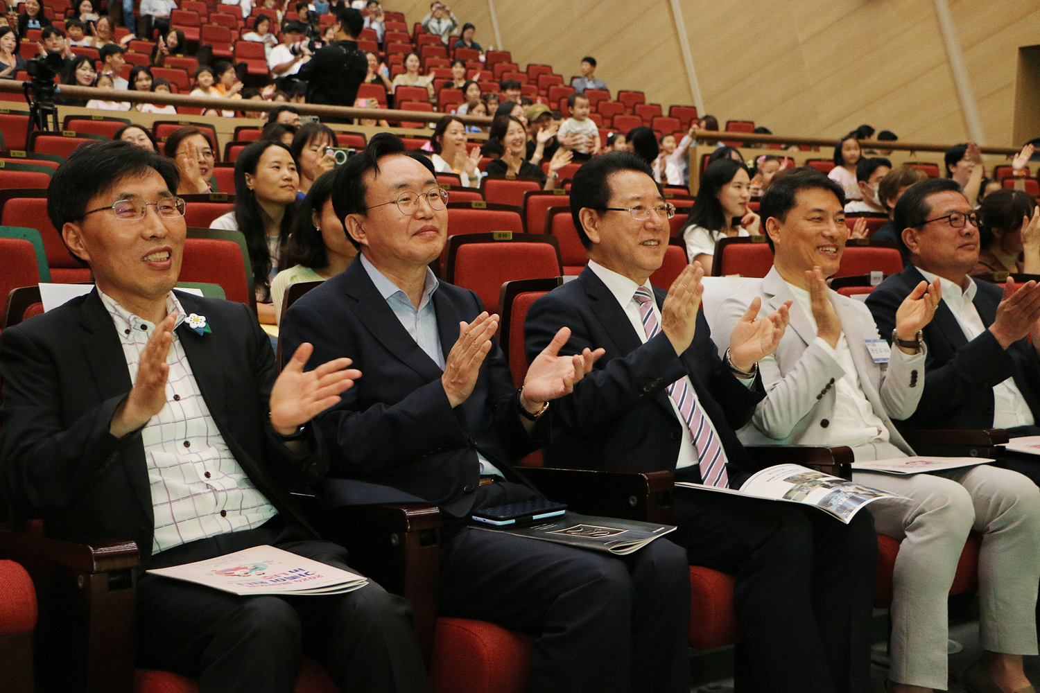 광주CBS주최 육아포럼 트니트니 탐험대의 공연을 보고 자리에 앉은 전라남도지사, 나주시장이 박수를 치고 있는 모습