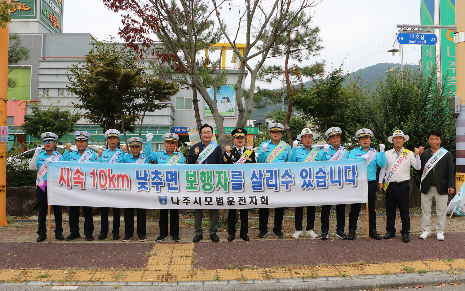 민, 관, 경 합동 어린이 교통안전 캠페인 나주시장고 나주경찰서장이 나주시 모범운젖자회 회원들홍보 현수막을 펼치고 화이팅을 하며 기념촬영을 하고 있는 모습