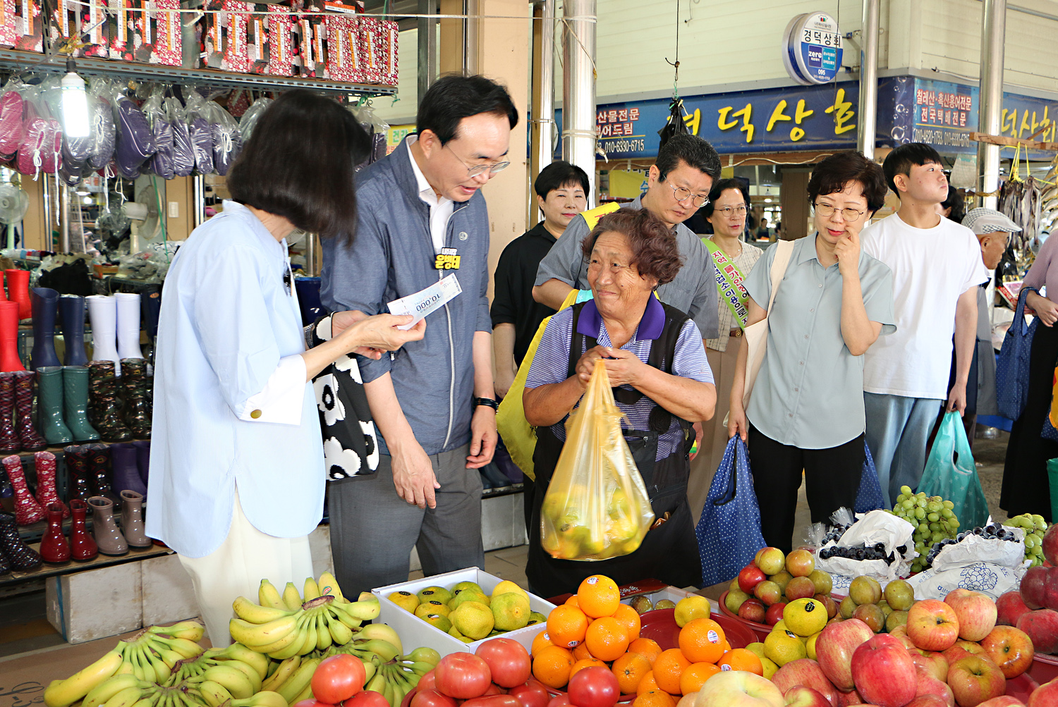 추석 명절맞이 나주목사고을시장 장보기 행사 나주시장과 배우자가 과일가게의 여성 상인에게 과일을 구매하고 전달 받으려고 하는 모습 배우자의 손에는 나주사랑상품권이 들려 있다