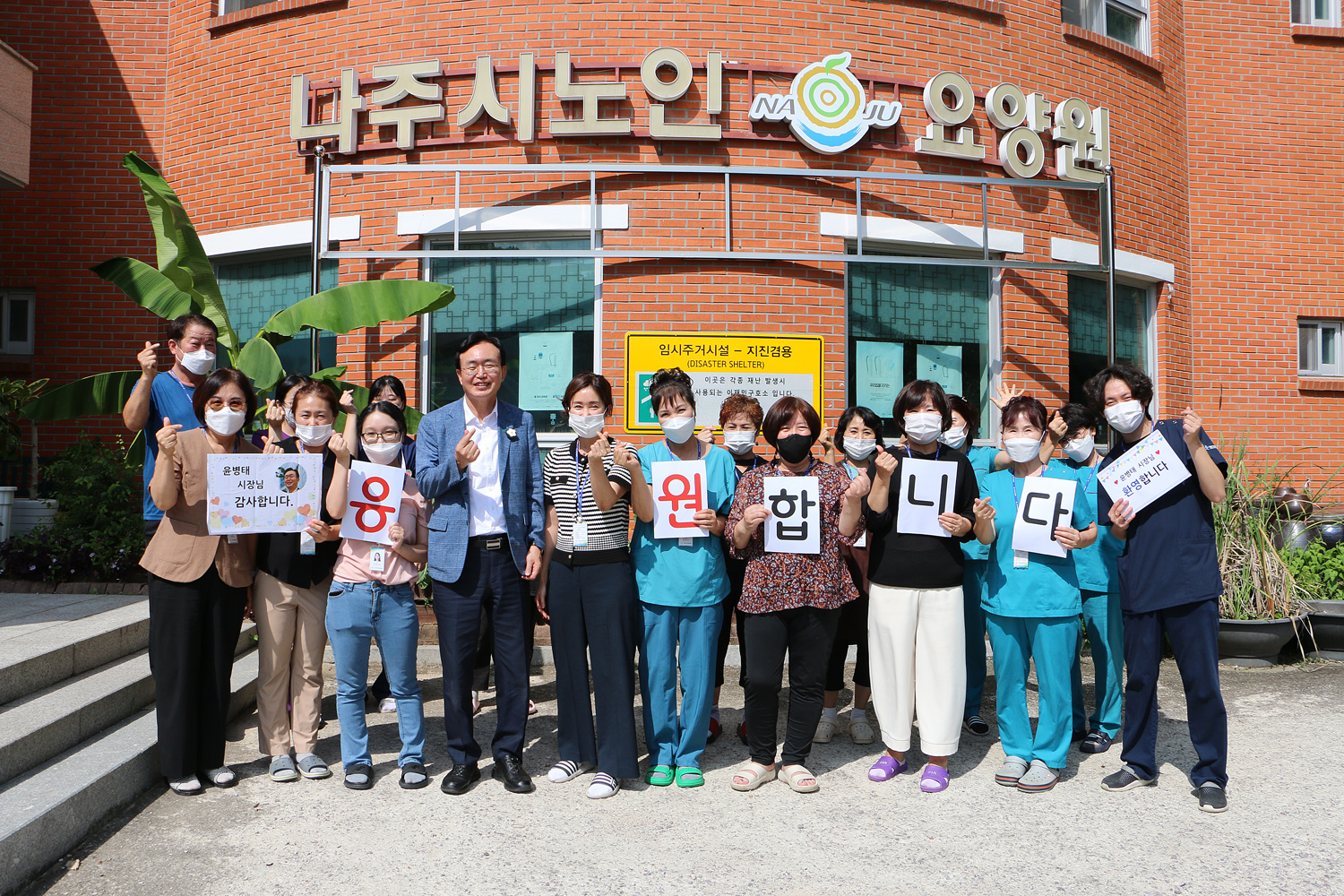 추석맞이 사회복지시설 위문 나주시장과 나주시노인요양원 전체 직원이 요양원 앞에서 손하트를 하며 기념촬영을 하고 있는 모습