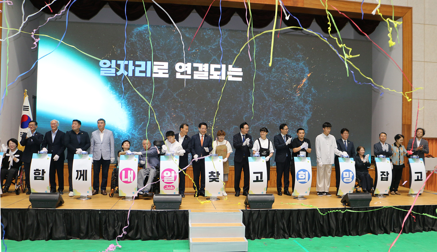 2024 전라남도 장애인 일자리 박람회 기념 세레모니 터치 버튼을 누른  후 축포가 터진 모습 단상 위의 내빈들의 모습이 보인다