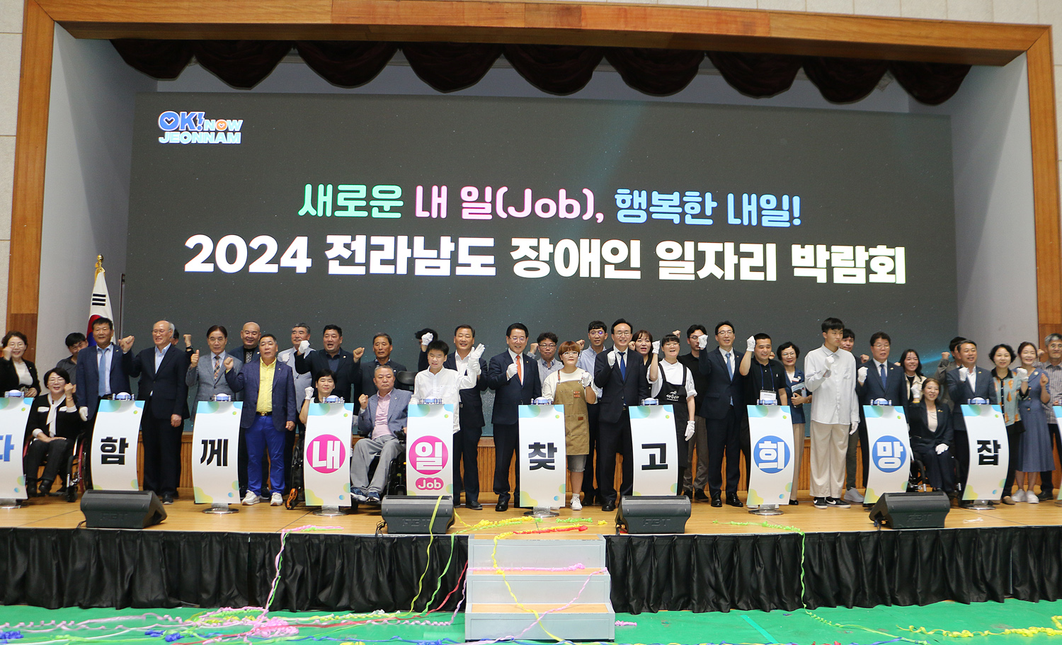 2024 전라남도 장애인 일자리 박람회 전라남도지사, 나주시장, 나주시의회 의장, 내빈 및 관계자 전체 무대 위에서 화이팅을 외치며 기념촬영을 하고 있는 모습