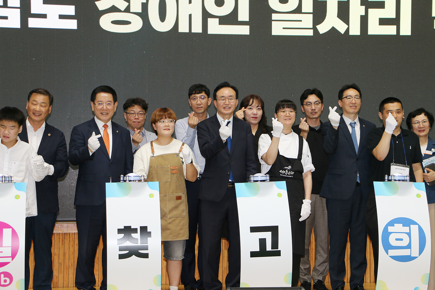 2024 전라남도 장애인 일자리 박람회 전라남도지사, 나주시장, 장애인 소년, 소녀들이 무대 위에서 손하트를 하며 기념촬영을 하고 있는 모습