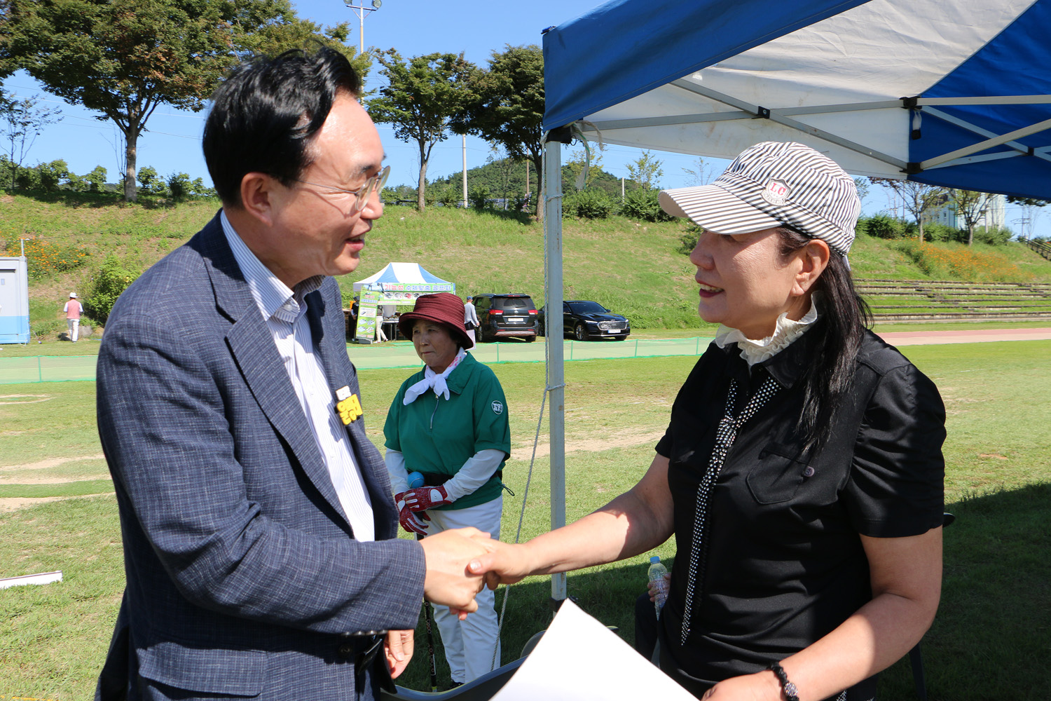 나주시장배 광주 전남 파크골프 대회 나주시장이 개회식장 한편에서 여성 관계자와 악수를 나누며 이야기를 하고 있는 모습