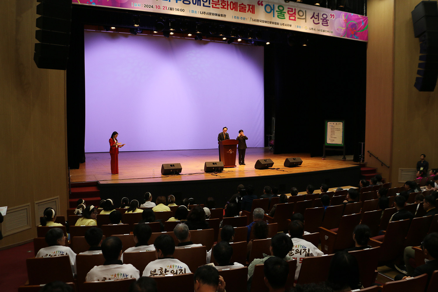 제1회 나주 장애인 예술제 나주시장이 단상에서 축사를 하는 모습과 참석자들의 앉아 있는 뒷모습 좌측면에서 촬영