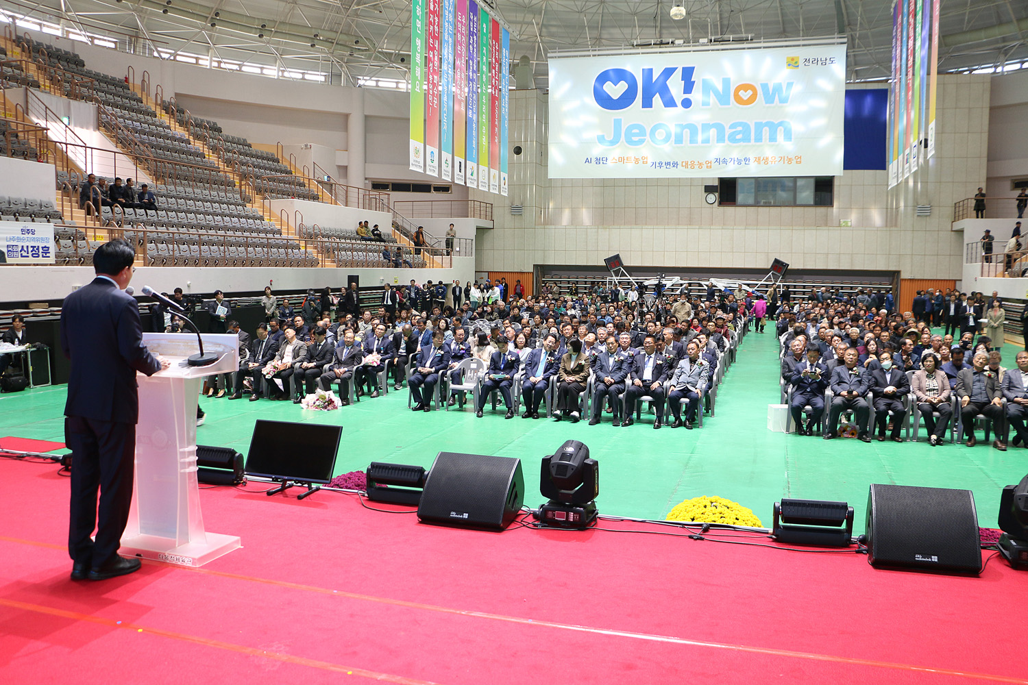 제29회 농업인의 날 기념행사 축사를 하고 있는 나주시장의 우측 뒷편에서 촬영한 나주시장의 뒷모습과 참석자들이 앉아 있는 앞모습이 함께 보인다