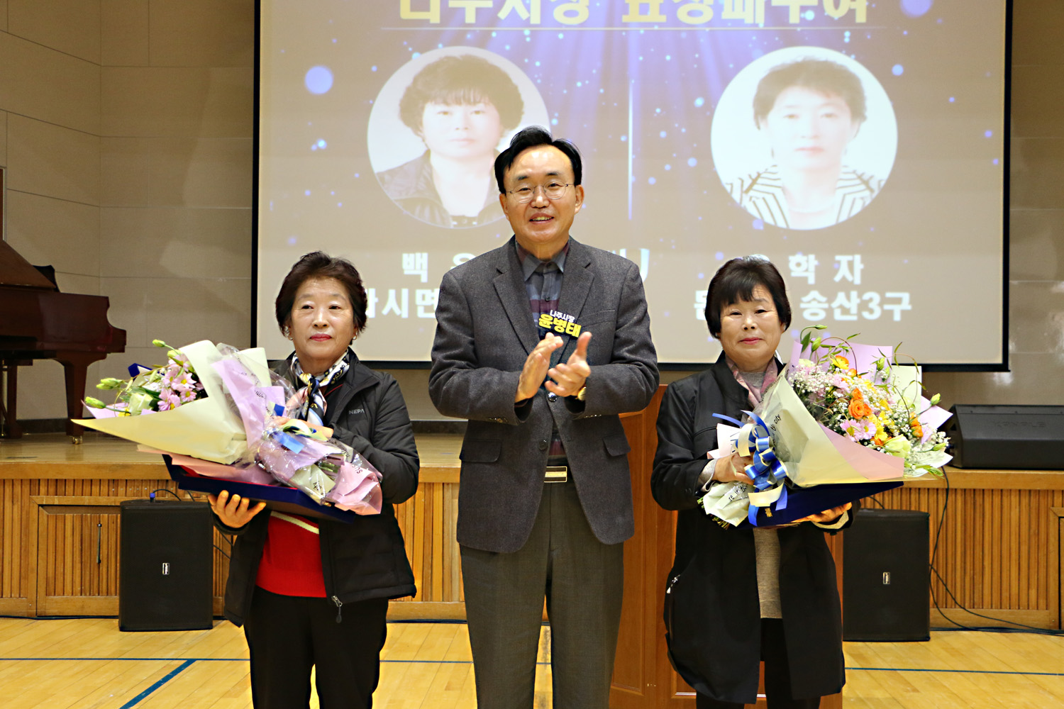 다시농협 여성조합원 교육 나주시장이 여성 2명에게 감사패를 전달한 후 함께 기념촬영을 하고 있는 모습