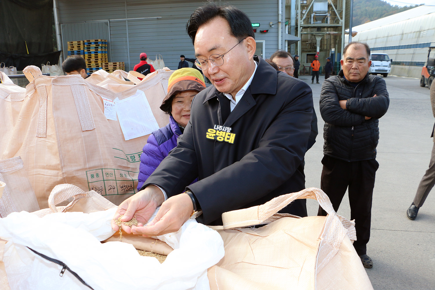 봉황농협 APC 수매현장 방문 나주시장이 손바닥에 올려놓은 믹곡을 톤백에 다시 담고 있는 모습