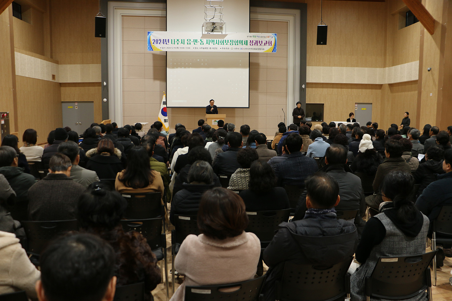 읍면동 지역사회보장협의체 성과보고회 나주시장의 축사모습과 참석자들이 앉아 있는 모습 측면촬영