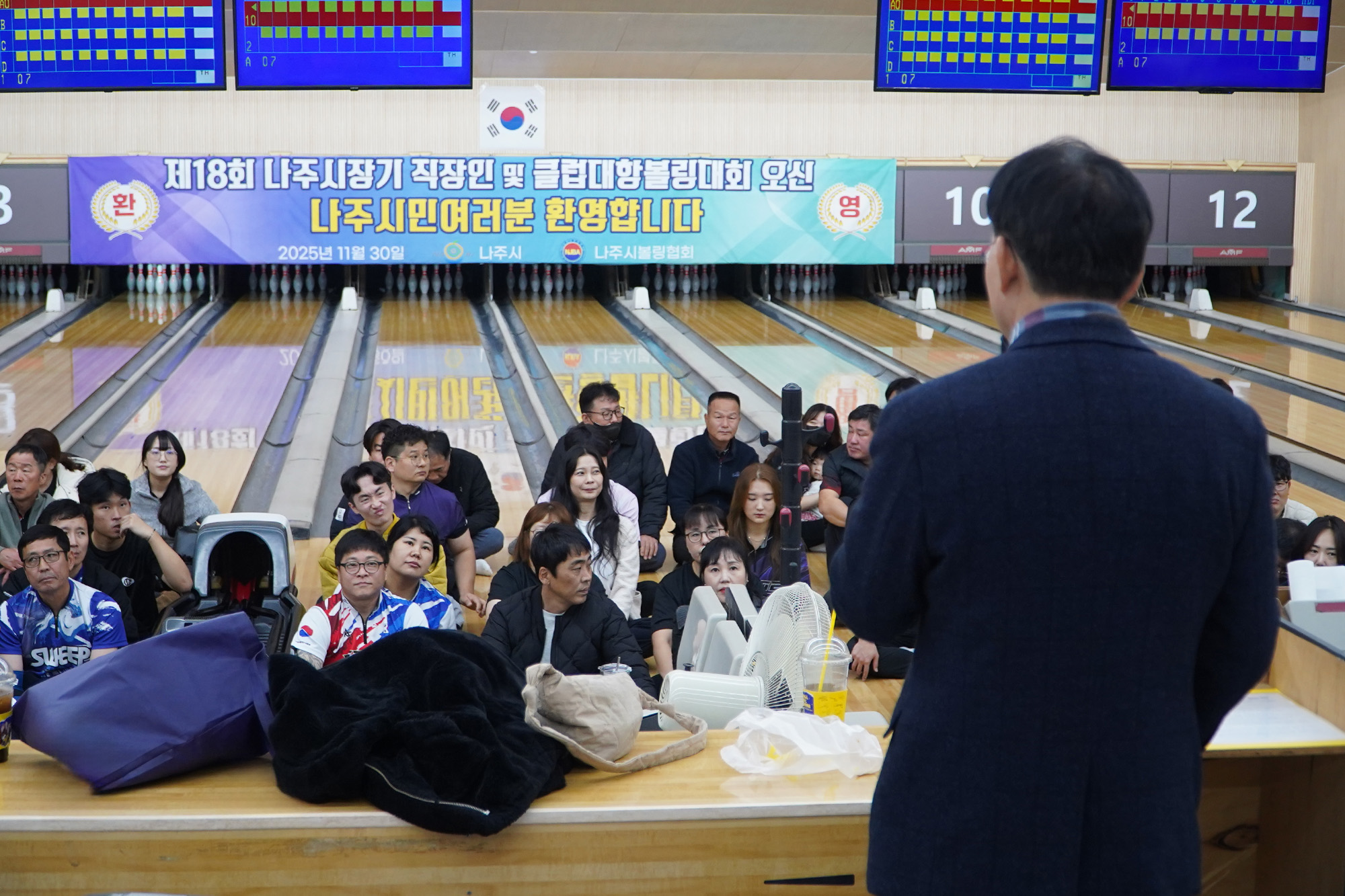 윤병태 나주시장이 뒷모습을 보이며 앉아있는 관중들에게 연설하고 있다. 관중들은 볼링 레인 앞에 앉아 경청하고 있으며, 레인 위에는 대회 현수막이 걸려있다.