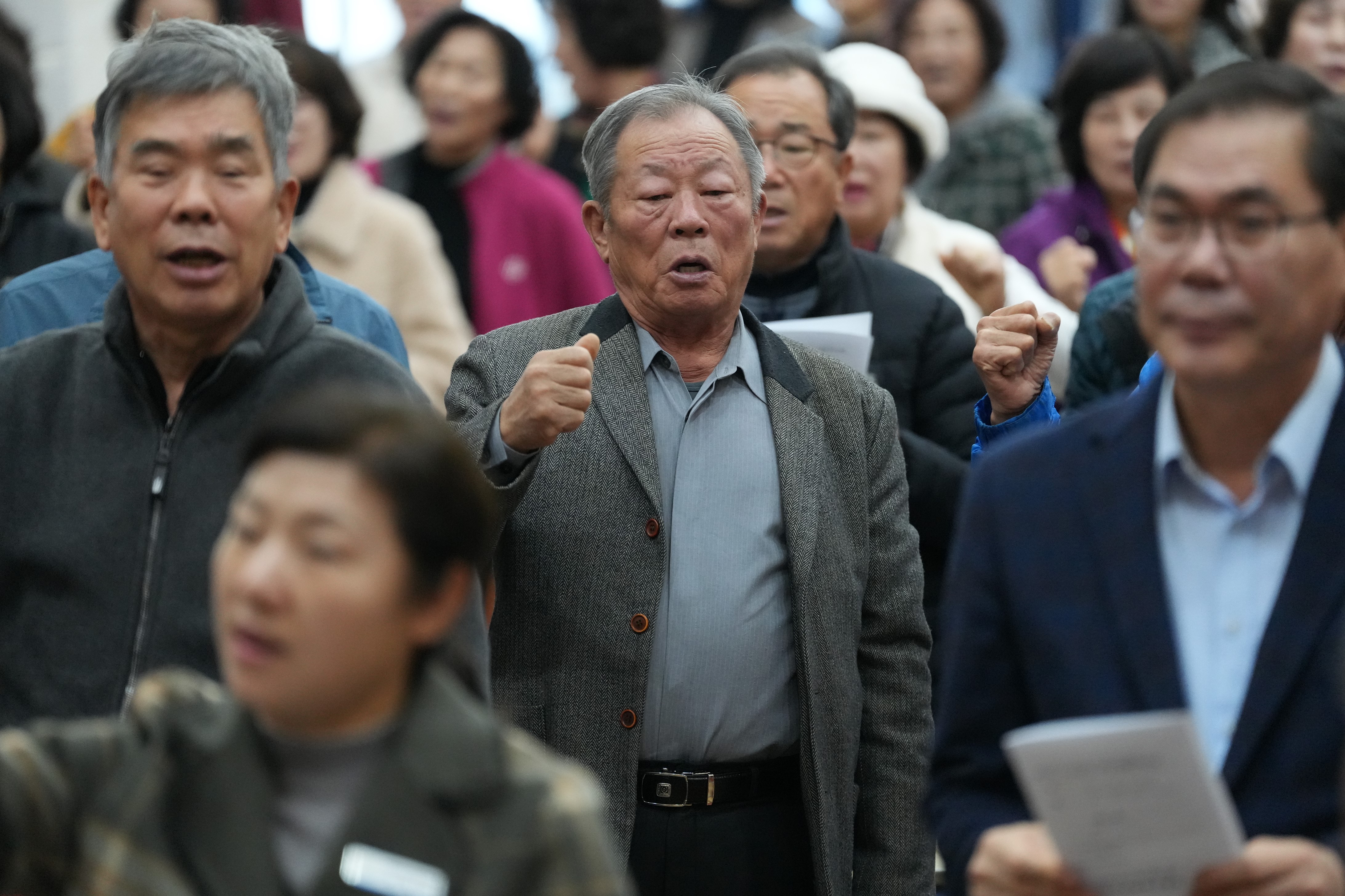 농민 행사 참석자들이 모여 있는 모습. 가운데의 중년 남성이 주먹을 쥐고 구호를 외치거나 열정적으로 환호하고 있으며, 주변 사람들도 함께 호응하고 있다.