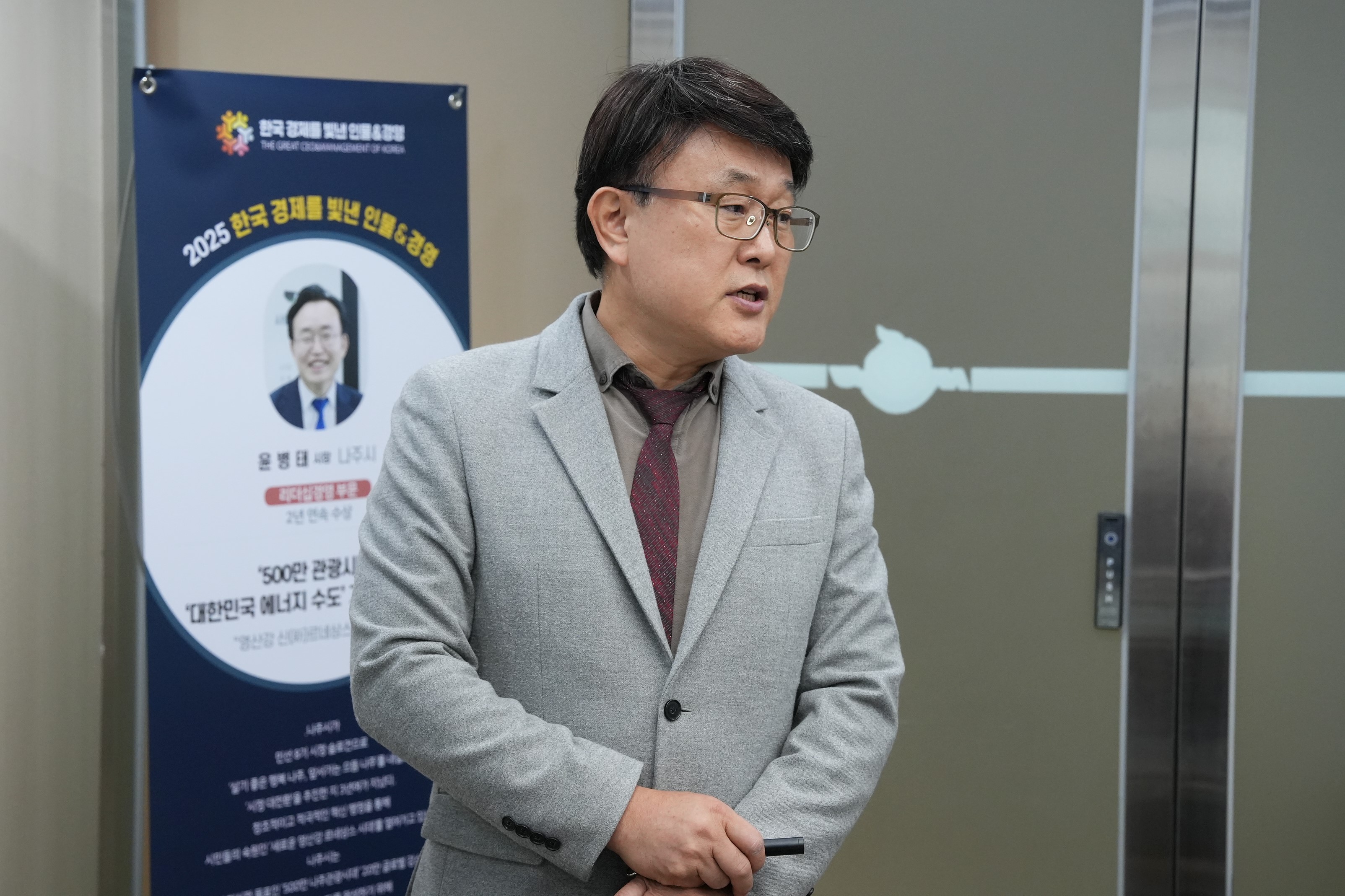  정장 차림의 한 남성이 서서 이야기 하는 모습