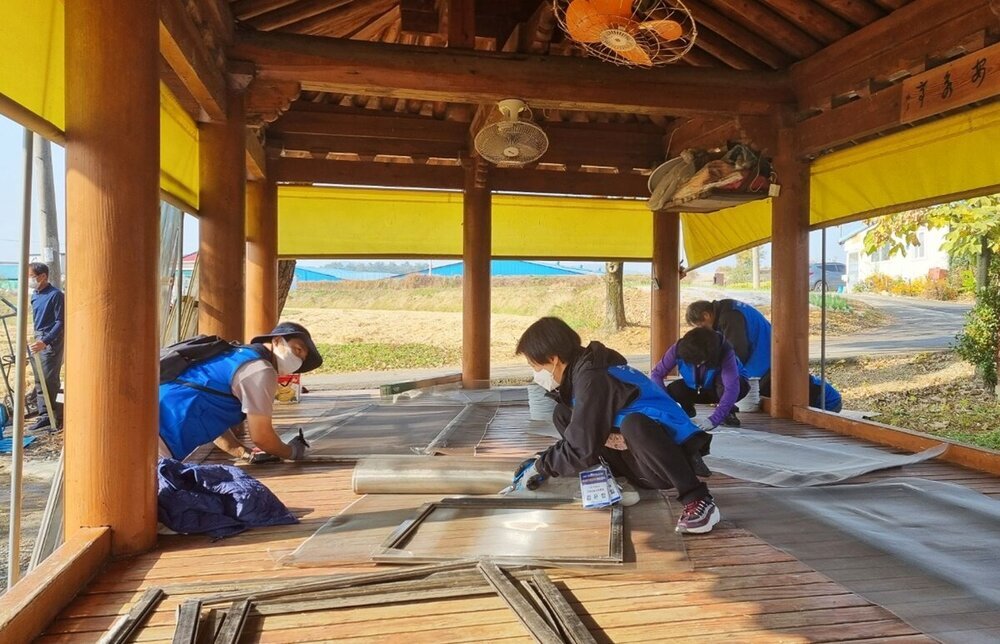 전남블루재능봉사단 나주 문평면 안영마을에서 주거환경개선 봉사 활동으로 정자에서 창틀에 방충망을 다시 설치하는 모습이다.