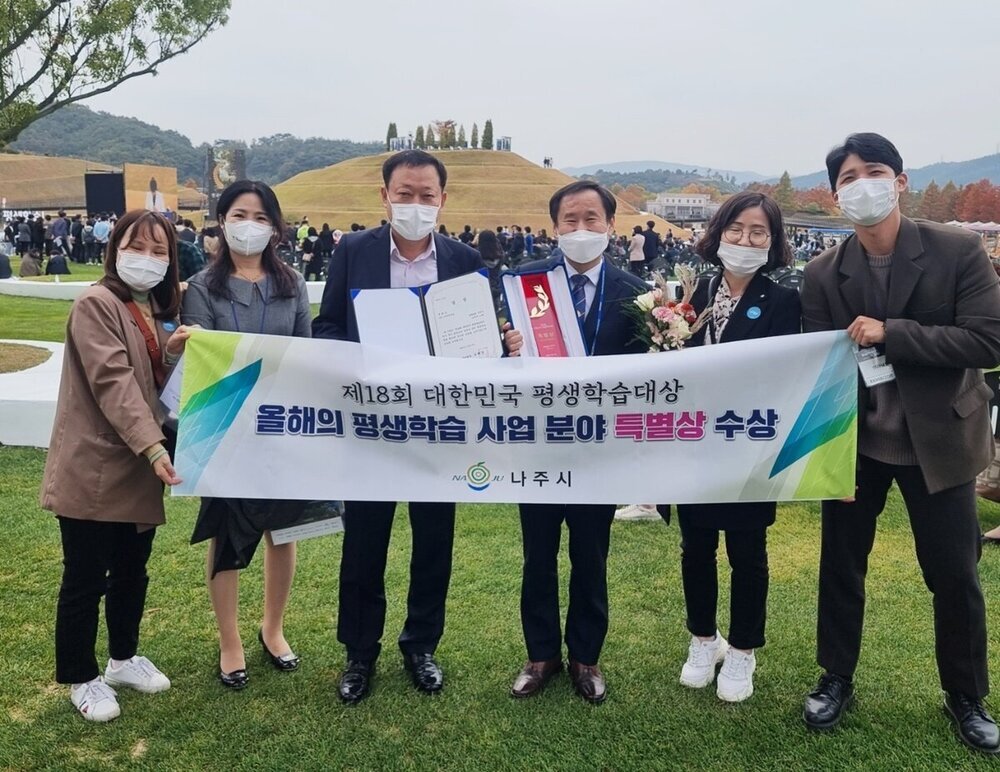 나주시, 제18회 대한민국 평생학습대상 특별상 수상이라고 적힌 현수막을 들고 수상자들이 기념촬영을 하고 있다