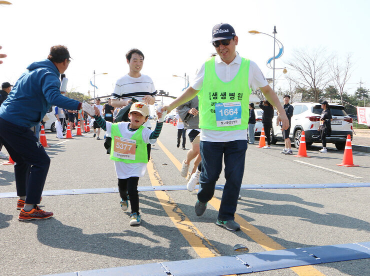 제9회 나주 영산강 마라톤대회 대회에 참석한 참가자인 아빠와 아들(어린이)이 완주를 하며 결승점으로 들어오고 있는 모습