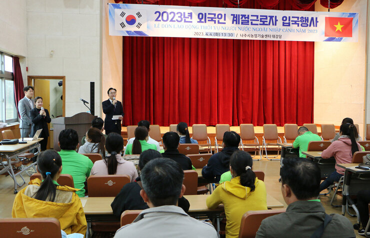 베트남 외국인 계절근로자 1차 입국행사 참석한 외국인 근로자들의 뒷모습이 보이고 나주시장이 인사말을 하고 있는 모습