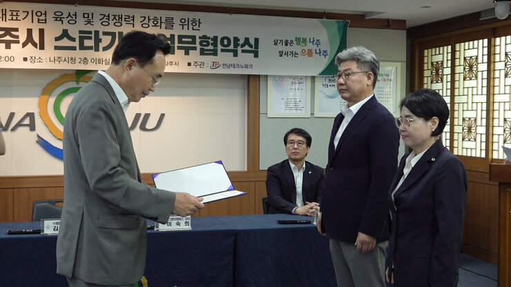 2023 나주시 스타기업 육성사업 업무 협약식 나주시장이 스타기업 대표 2명에게 협약서를 전달하는 모습