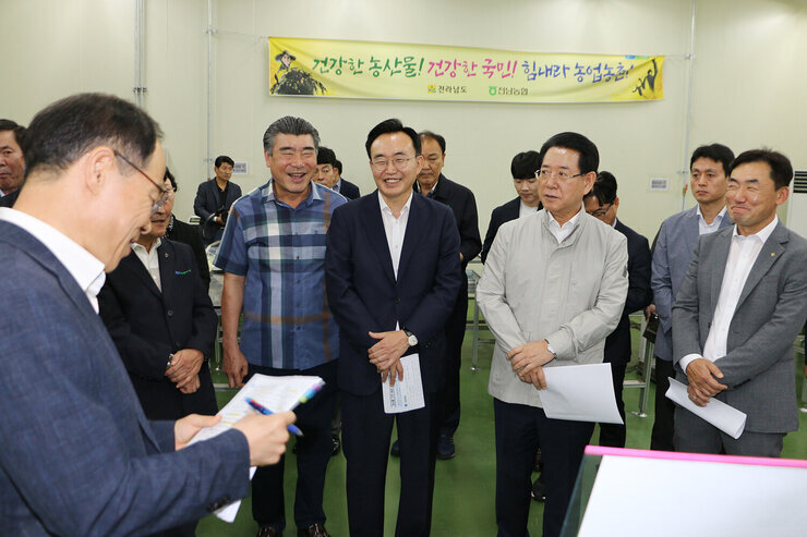 친환경농산문 종합물류센터 전남도지사 방문 전남지사와 나주시장, 도의원이 도청 담당국장에게 보고를 받으며 웃고 있는 모습