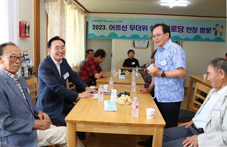문명면 무더위 쉼터 방문 남성 어르신이 자리에 서서 이야기를 하고 있고 나주시장과 옆에 앉아 있는 남성 어르신이 웃고 있는 모습