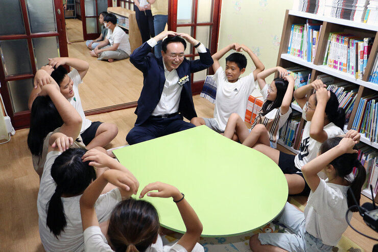 송월지역아동센터 방문 간담회 나주시장이 센터의 아이들과 양팔로 하트를 그리며 인사를 나누는 모습