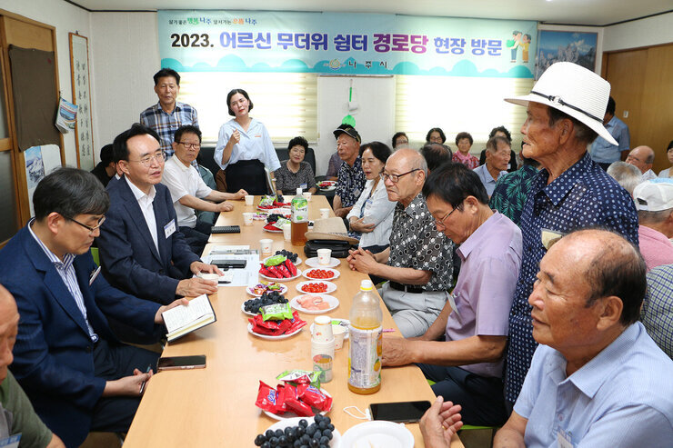 세지면 무더위 쉼터 방문 남성 어르신 한분이 자리에 서서 나주시장에게 질문을 하고 있고 나주시장이 듣고 있는 모습