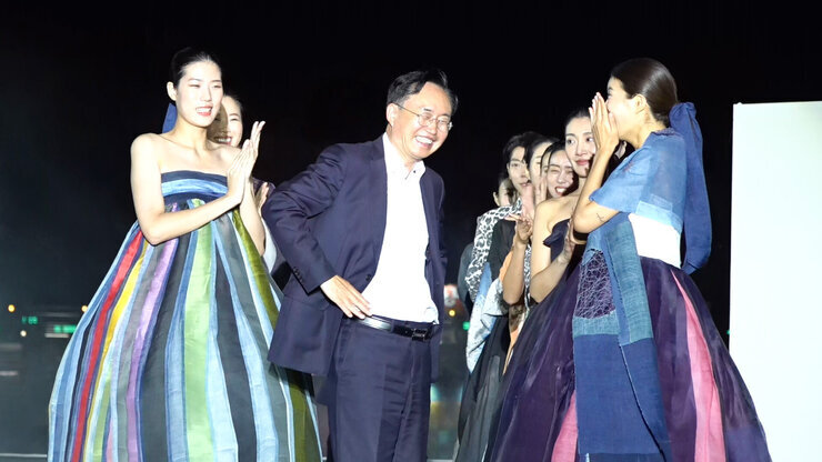 나주축제 - 천연염색 패션쇼 나주시장이 양 옆의 여성 모델들 사이 중간에서 허리춤에 손을 얹고 포즈를 취하고 있는 모습