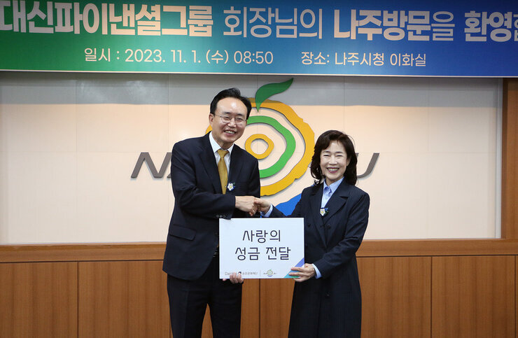 대신파이낸셜 그룹 회장 나주방문 나주시장과 대신그룹 회장이 악수와 성금전달 판을 들고 기념촬영을 하고 있는 모습