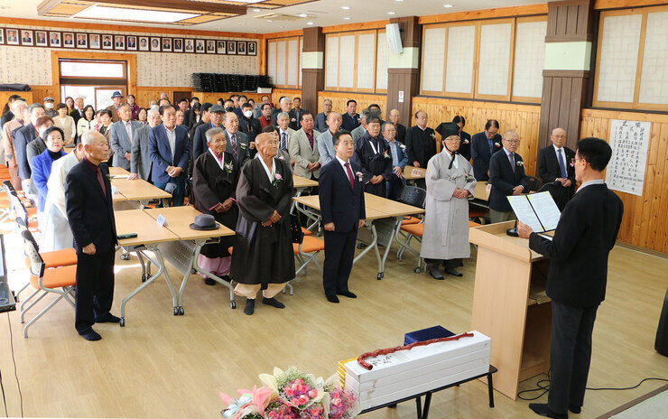나주향교 기로연 향교 대표자가 단상으로 나와서 윤리선언문 낭독을 하고 있고 참석자들이 자리에 서 있는 모습 전체