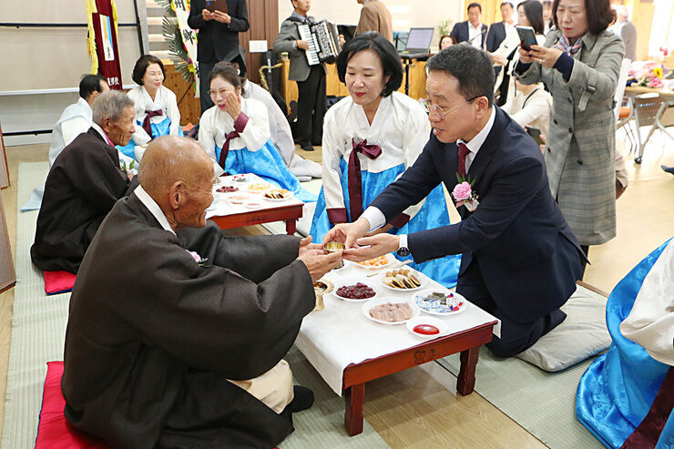 나주향교 기로연 기로연장 앞쪽에 마련된 음식상에 장수상을 받은 어르신이 앉아 있고 나주시 부시장이 맞은편에서 술을 올리고 있는 모습