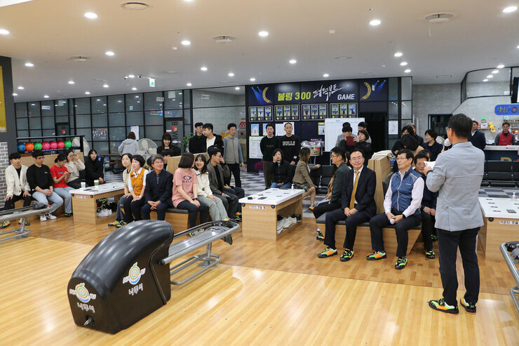 나주시 공무원 청렴볼링대회 결승전 시상 시상식을 위해 볼링장에 직원들과 나주시장이 앉아 있고 대회 담당직원분이 마이크를 잡고 진행하고 있는 모습