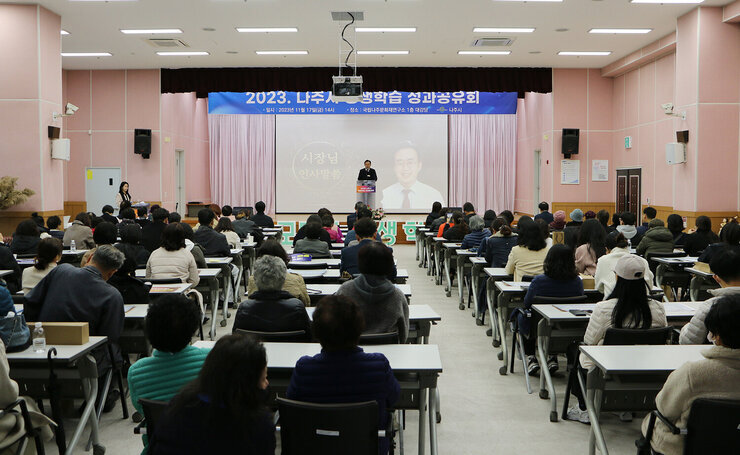나주시 평생학습 성과 공유회 나주시장의 인사말 모습과 참석자들이 뒷모습 전면