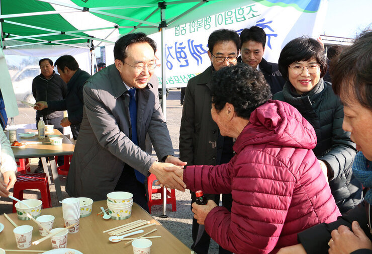 공공비축미곡 수매현장 나주시장이 여성 농민과 악수를 나누며 인사를 하고 있는 모습