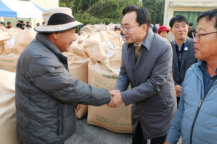 공공비축미곡 수매현장 방문 나주시장이 모자를 쓴 남성 농민과 악수를 하며 이야기를 나누는 모습