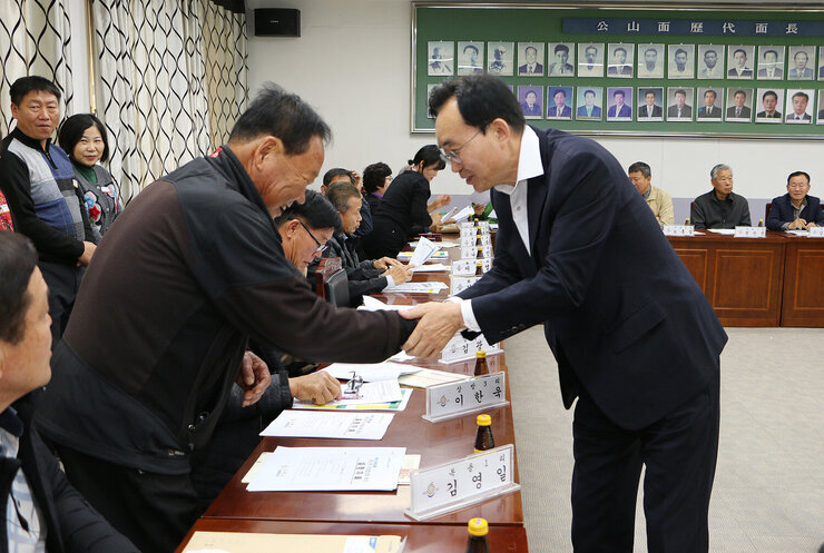 공산면 이장협의회 월례회의 나주시장이 자리에 앉아 있는 이장님과 악수를 하며 인사를 나누는 모습