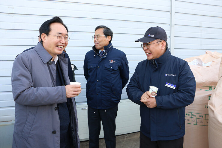 공공비축미곡 수매현장 나주시장이 미소를 지으며 남성 검사관의 이야기를 듣고 있는 모습