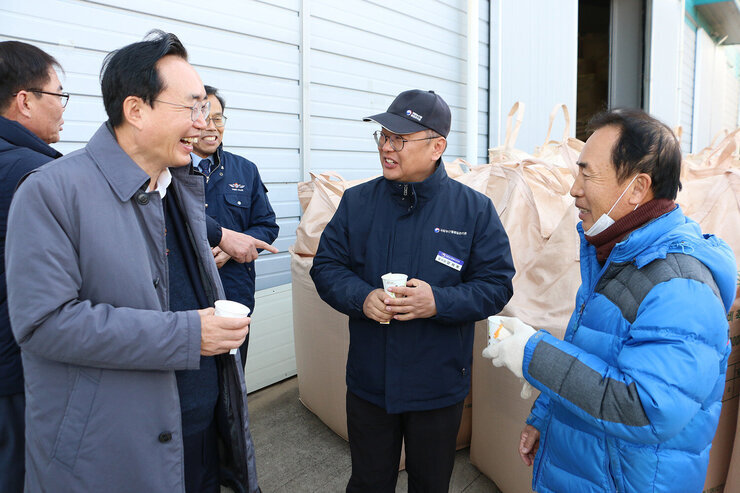 공공비축미곡 수매현장 남성 검사관과 농민 나주시장이 창고 앞에 서서 웃으며 대화를 나누는 모습