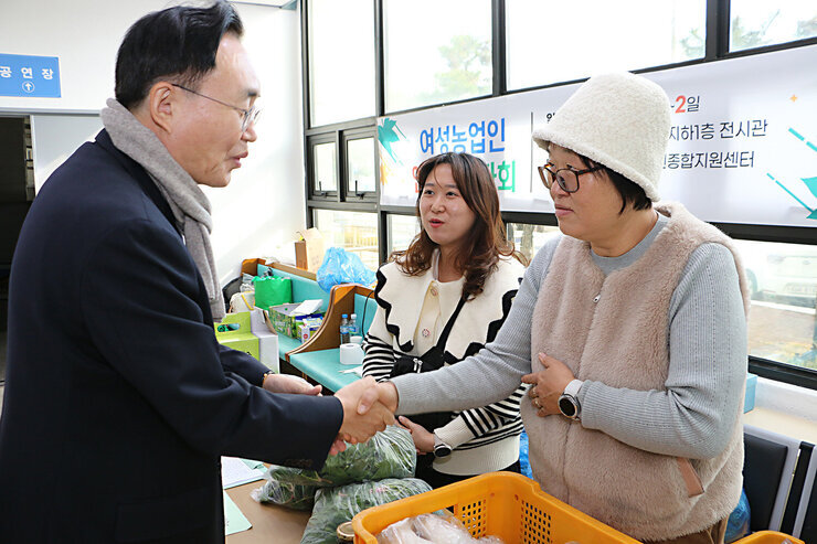 여성 농업인 그림 전시회 나주시장이 여성농업인 바자회 여성 관계자와 악수를 나누고 있는 모습