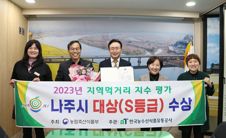 2023년 지역먹거리 지수 평가 대상 수상 나주시장과 농업기술센터 소장, 담당과장, 담당 팀장 및 직원이 플래카드를 펼치고 기념촬영을 하고 있는 모습