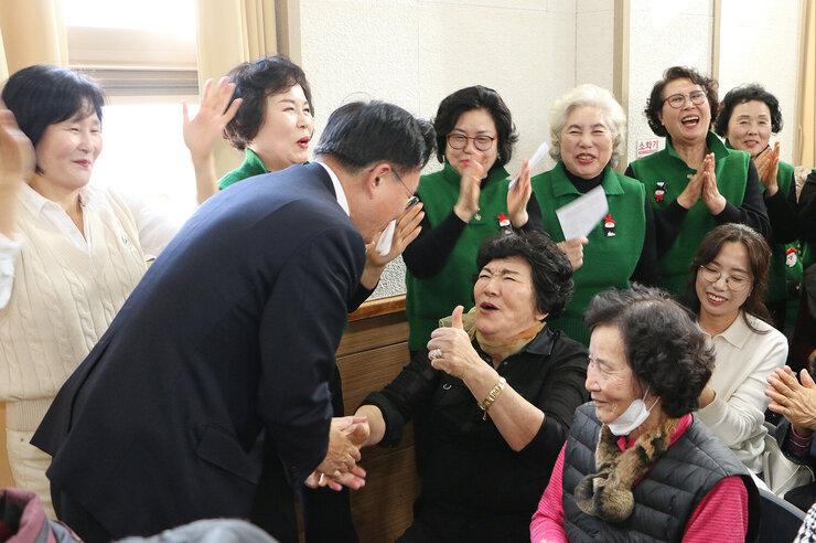 중부노인복지관 실버어울림 문화축제 자리에 앉아 있는 여성 어르신이 나주시장을 보며 한손으로 엄지손가락을 치켜 올리고 있고  한손은 나주시장의 손을 잡고 웃으며 대화를 나누는 모습