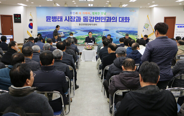동강면 주민과의 대화 남성 주민이 자리에 서서 질의를 하고 있는 뒷모습과 대화장의 대화석에 앉아서 나주시장이 듣고 있는 모습