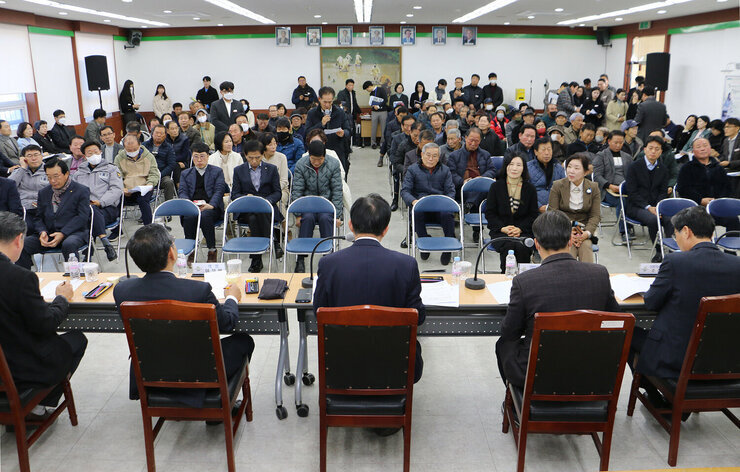동강면 주민과의 대화 남성 주민이 자리에 서서 질믜를 하고 있는 앞모습과 대화석에서 듣고 있는 나주시장, 간부공무원, 도의원, 시의원의 뒷모습 전면