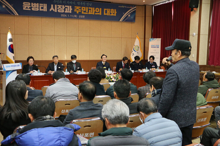 산포면 주민과의 대화 남성 주민분이 자리에서서 마이크를 잡고 질의를 하고 있고 대화석에서 나주시장이 듣고 있는 모습