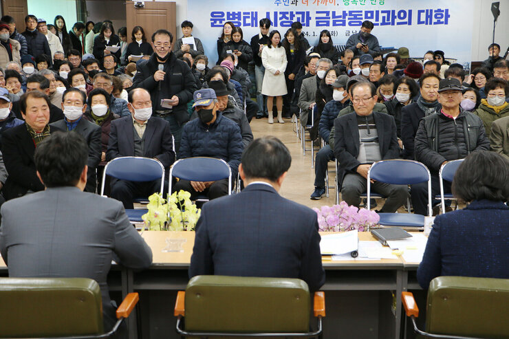 금남동 주민과의 대화 사진 좌측 앞에서 3번째 줄 남성 주민이 자리에 서서 질의를 하고 있고 대화석의 나주시장이 듣고 있는 모습