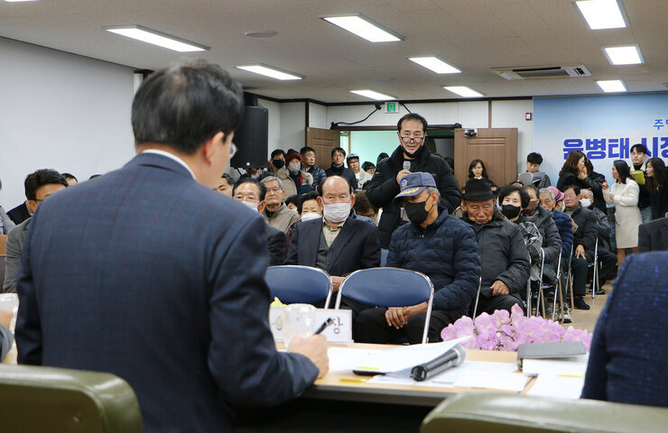 금남동 주민과의 대화 대화장 앞쪽의 남성 주민이 자리에 서서 질의를 하고 있고 나주시장이 펜을 잡고 듣고 있는  뒷모습