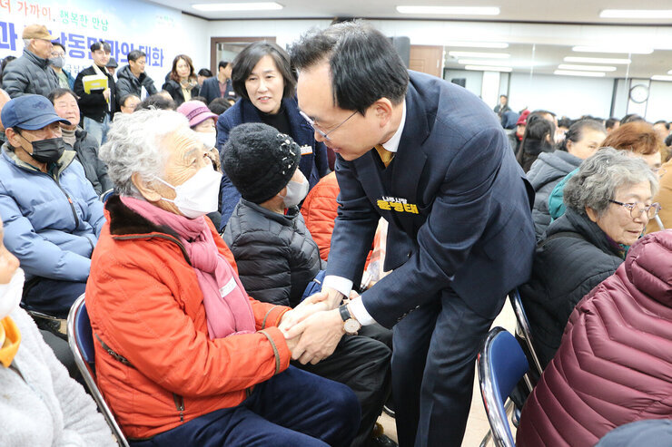 금남동 주민과의 대화 자리에 앉아 있는 여성 어르신과 두손을 맞잡으며 인사를 나누고 있는 나주시장의 모습